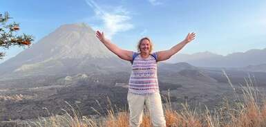 Im Hintergrund der Pico de Fogo und im Vordergrund eine Frau, welche die Arme nach oben streckt