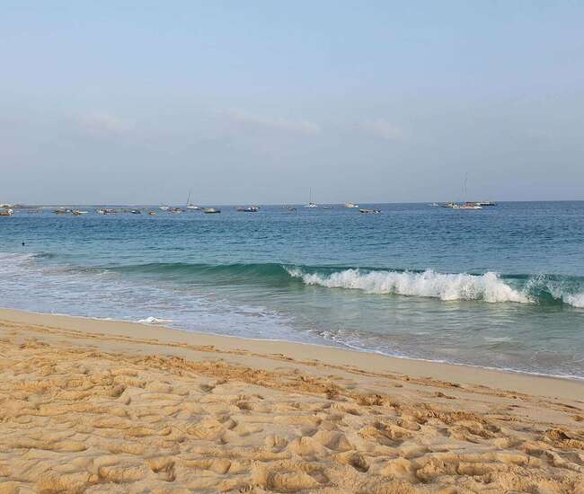 Sand und blaues Meer mit Wellen auf Sal