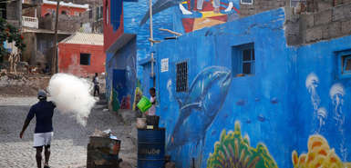 Street Art mit Meeresbewohnern, davor sind Einwohner des Fischerdorfes zu sehen