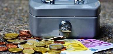 Geldkassette mit Euromünzen und -scheinen davor