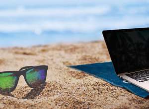Laptop und Sonnenbrille am Strand