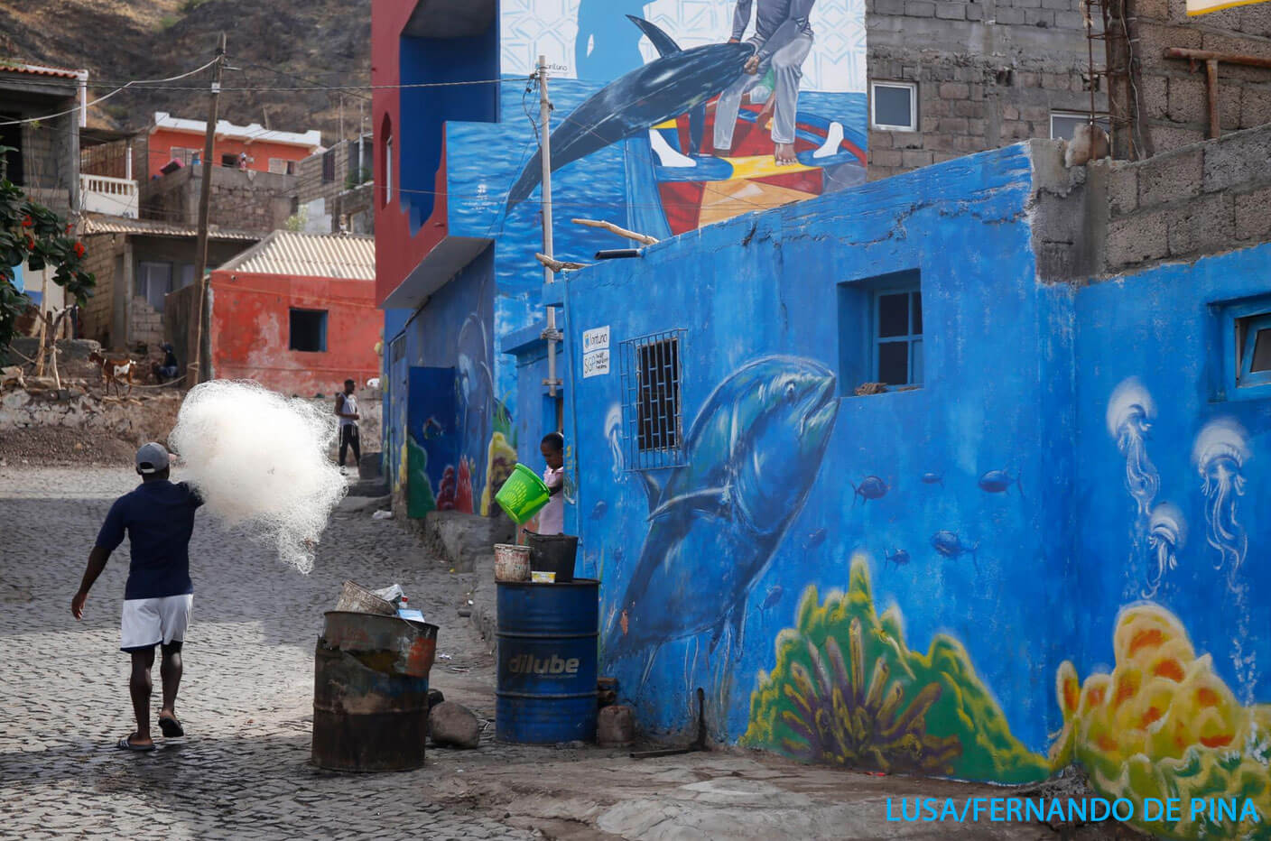 Street Art mit Meeresbewohnern, davor sind Einwohner des Fischerdorfes zu sehen
